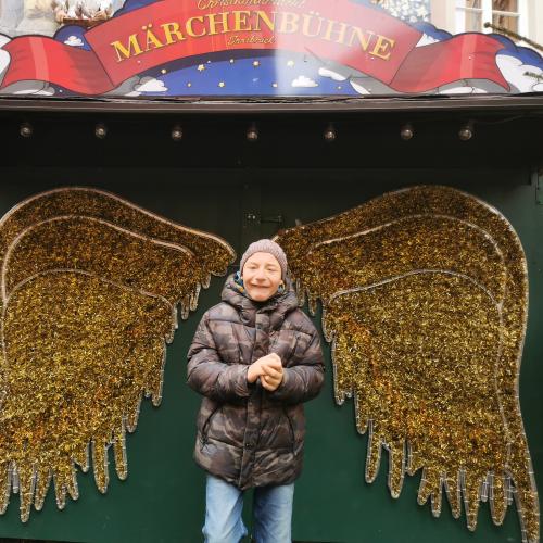 ein Schüler am Weihnachtsmarkt mit Engelsflügeln
