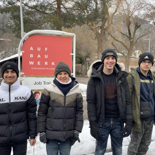 vier Jugendliche posen vor dem Schild des AufBauWerks